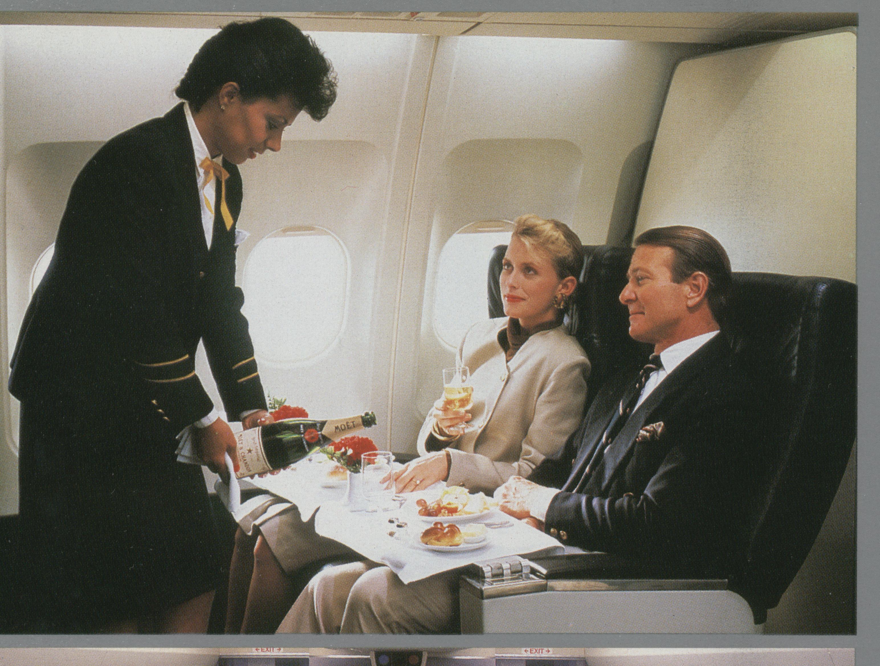 1990s A flight attendant serving customers in the First Class cabin of a Pan Am Airbus A310.  Pan Am used the long range, medium sized A310s to offer nonstop service from New York to smaller European cities such as Warsaw, Budapest, Oslo & Helsinki.